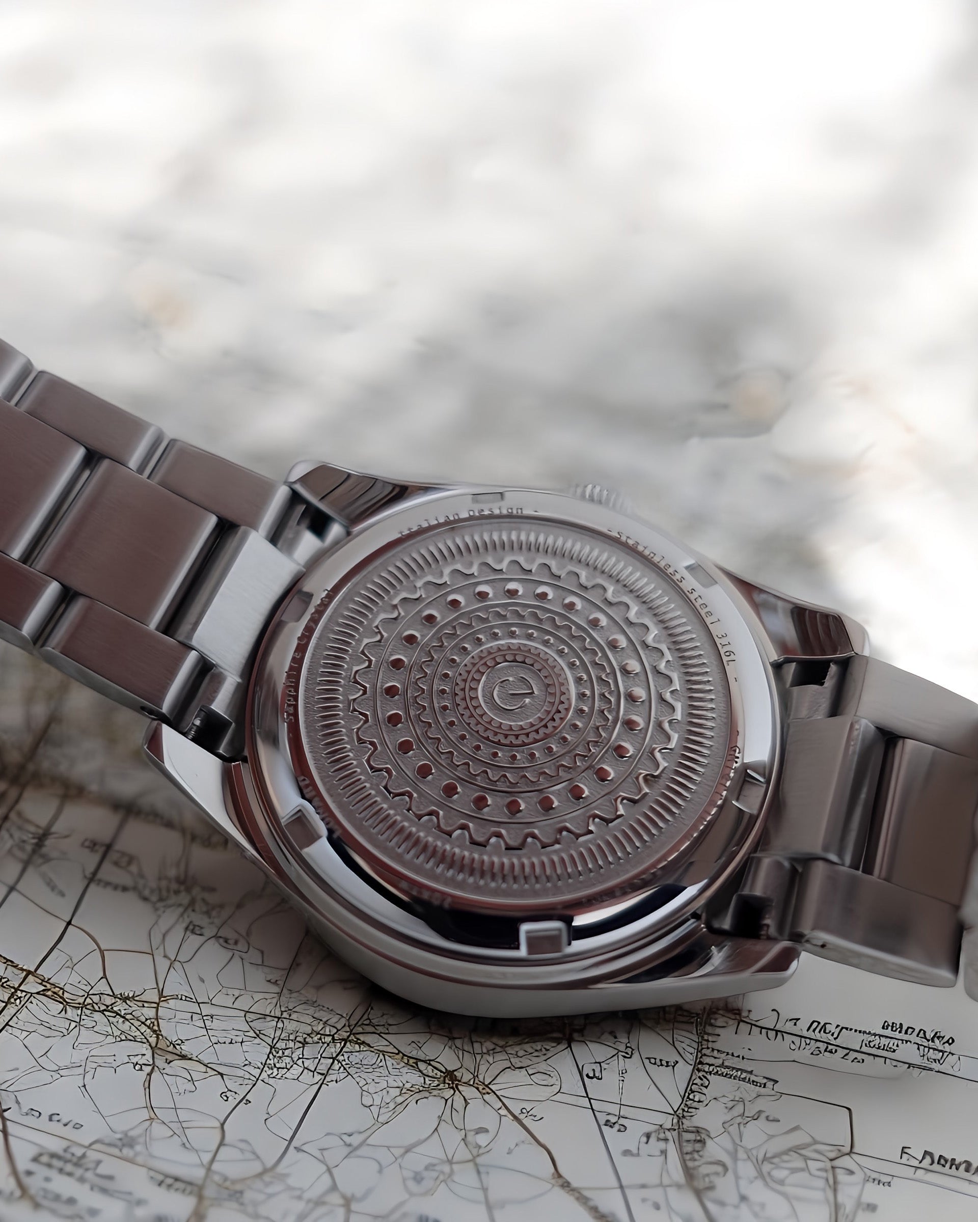 Back view of the Lonard TerraLuxe watch showcasing the engraved stainless steel caseback with concentric circular patterns, photographed on a vintage map background.
